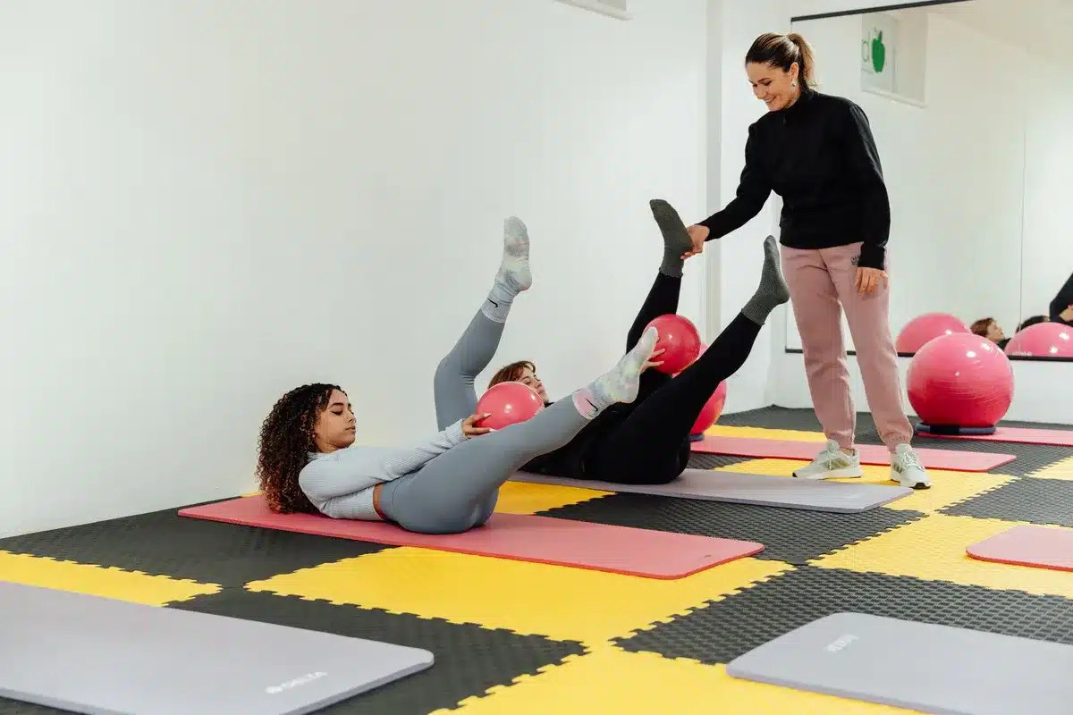 Femme allongée effectuant l'exercice du Hundred avec battements de bras contrôlés