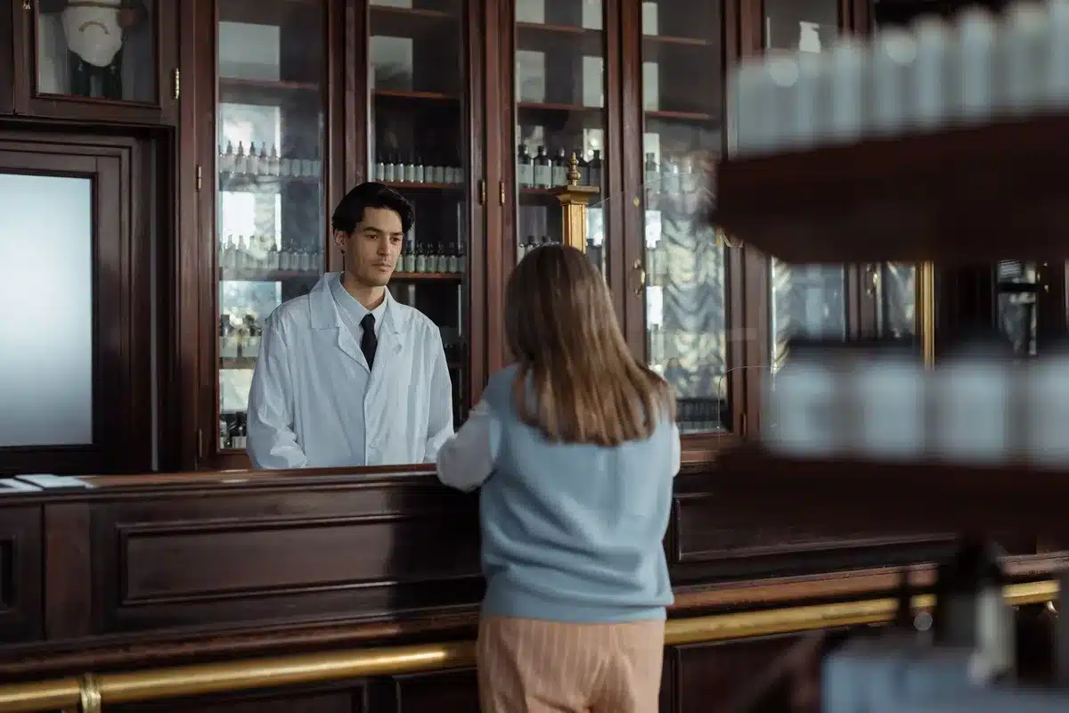 Pharmacien conseillant un patient sur la prise en charge et le remboursement d'un médicament