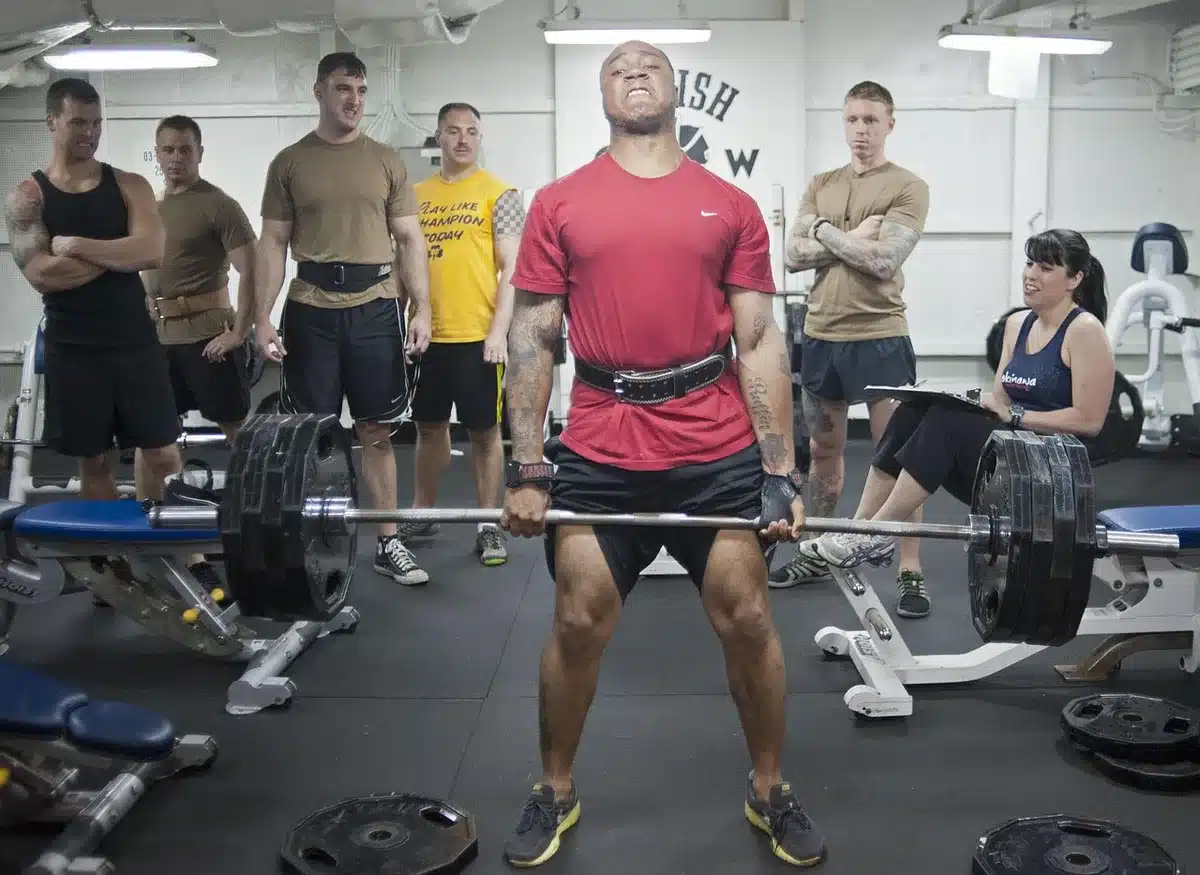 Vue rapprochée de muscles et d'un haltère en salle, illustrant la présence de glutamine dans les muscles