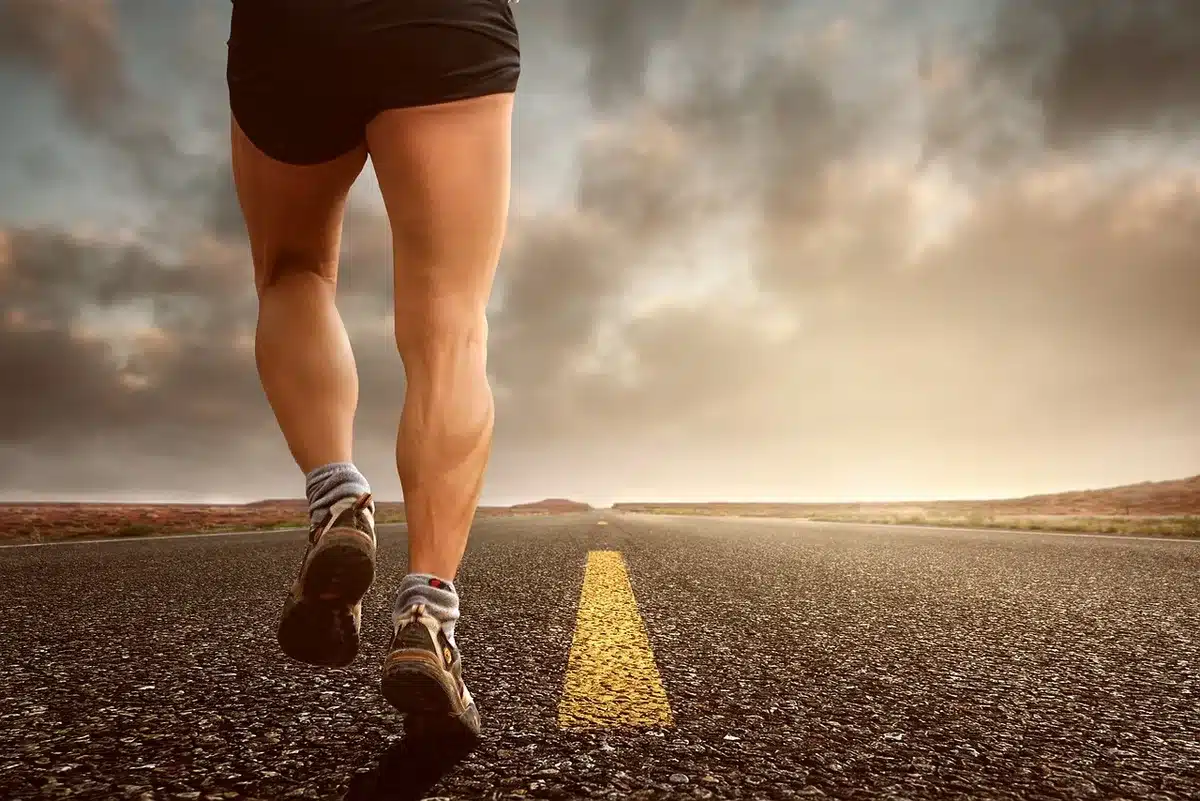 Coureur en tenue légère effectuant un footing par un parc en journée