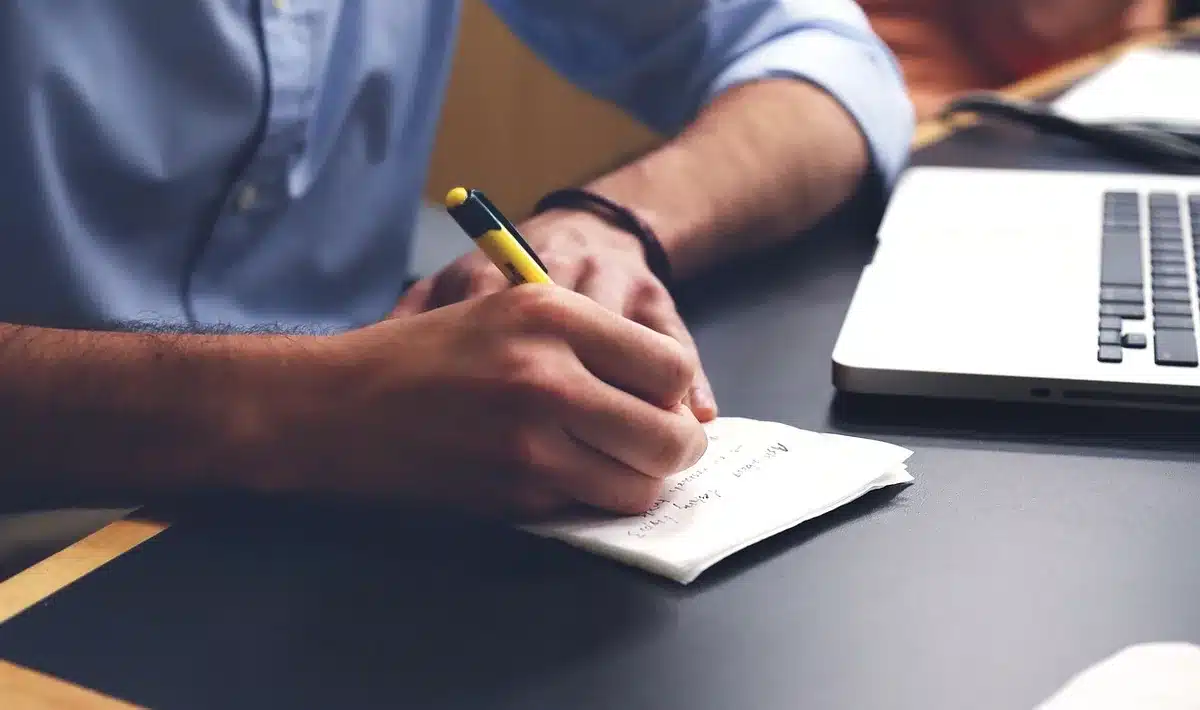 Cahier ouvert avec un plan d'entraînement hebdomadaire et crayon à côté d'une montre GPS