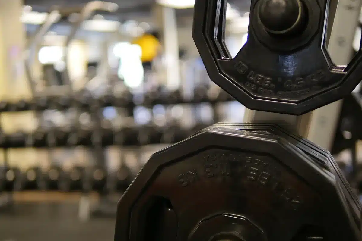 Personne pratiquant des exercices de renforcement avec haltères dans une salle lumineuse