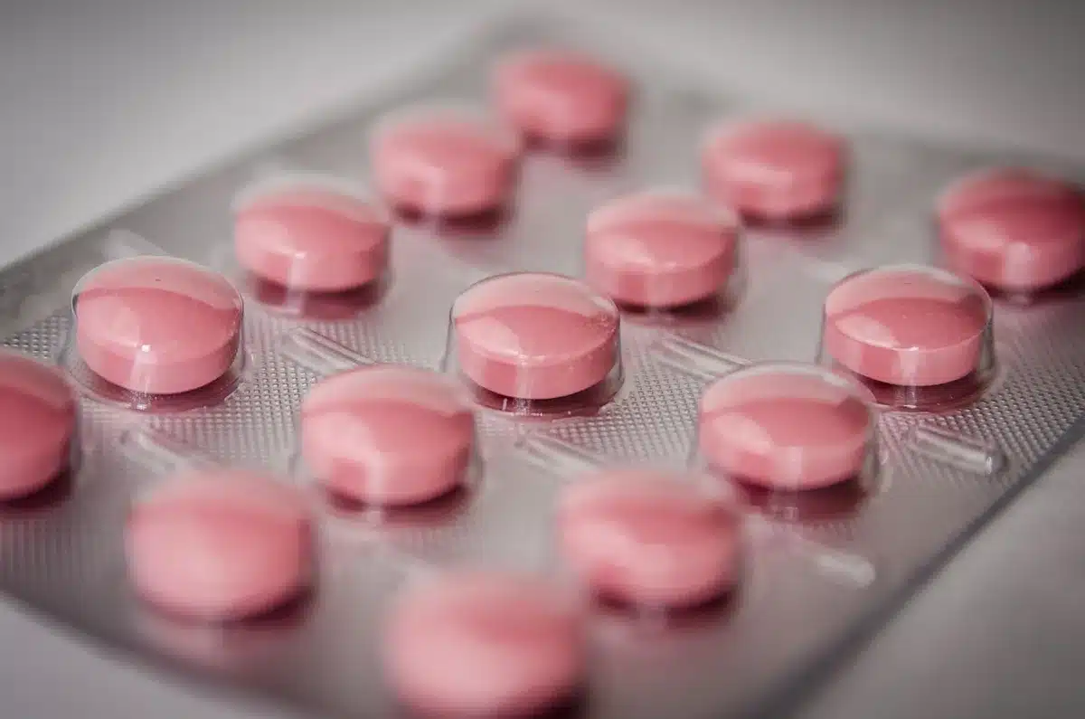 Carnet avec heures et doses notées à côté d'un organiseur de médicaments