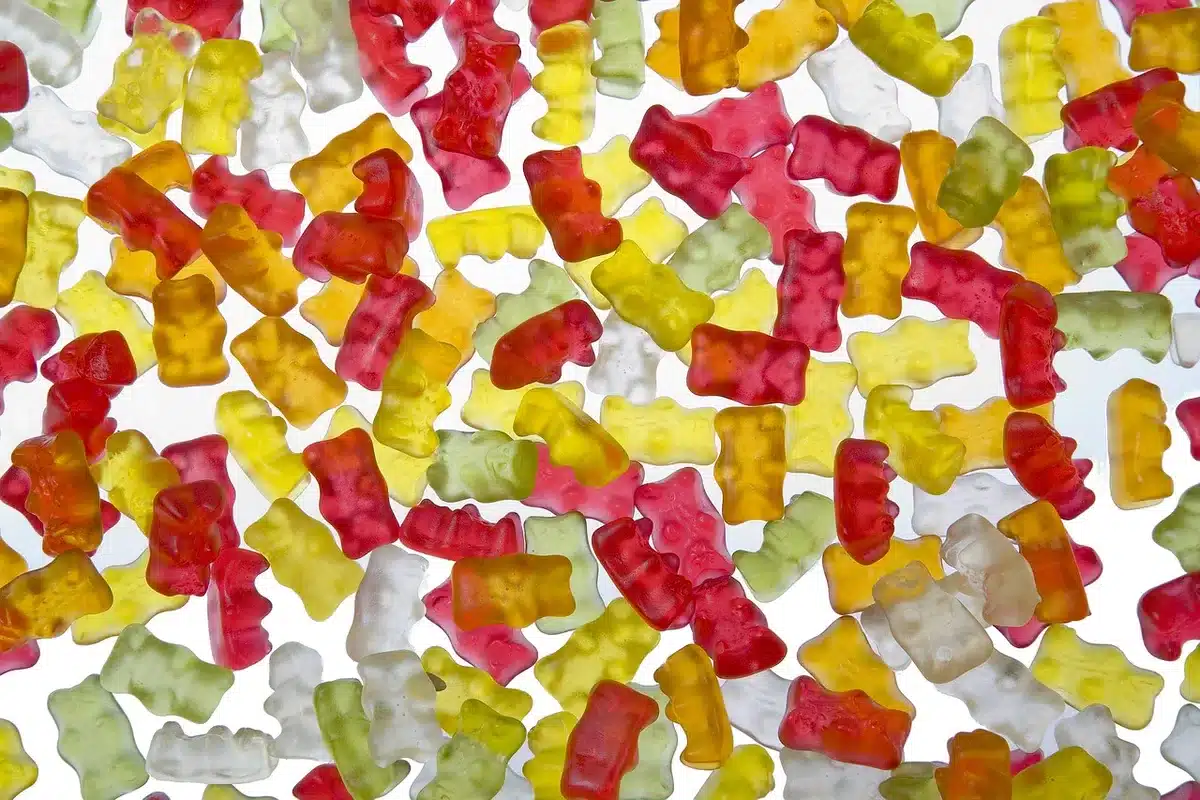 Poudre verte à côté de gummies sur une planche, comparaison visuelle