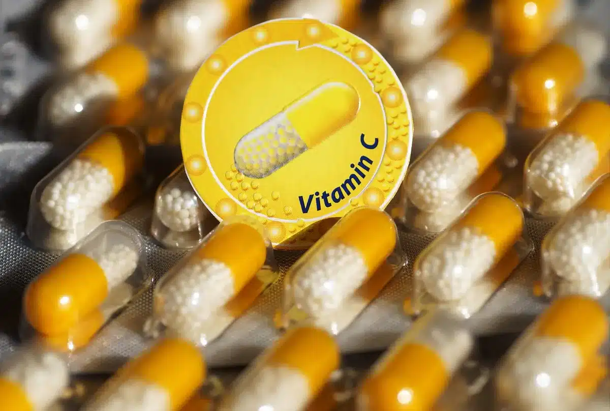Personne lisant l'étiquette d'un complément vitaminé près d'une fenêtre en journée
